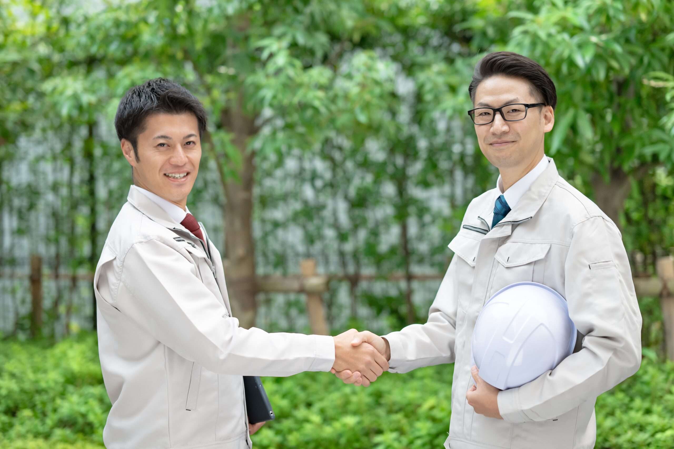 握手する作業着姿の人たち